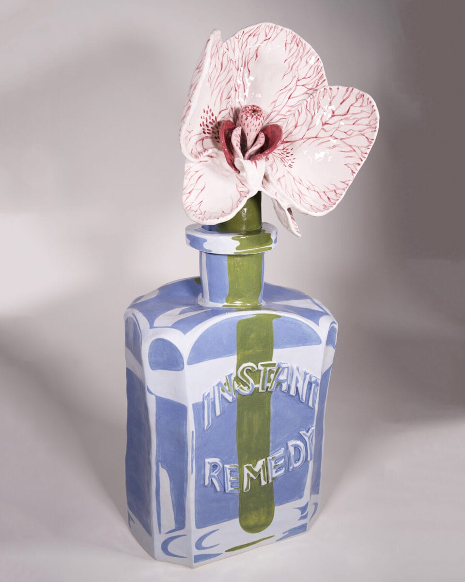 a ceramic sculpture of a glass bottle reading "instant remedy" holding a flower