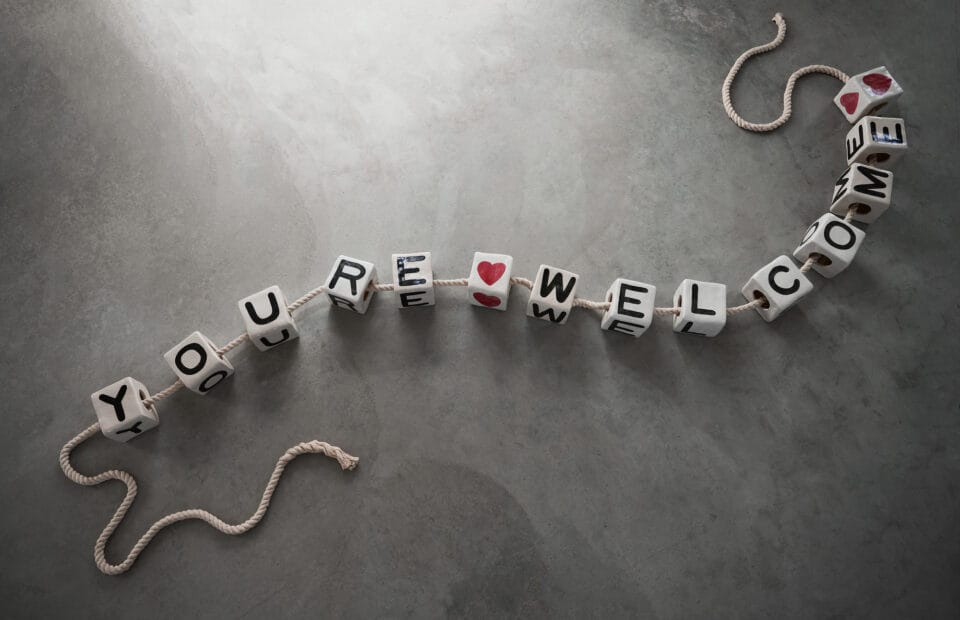 a sculpture of a charm bracelet made with ceramic beads. the beads read, "youre welcome"