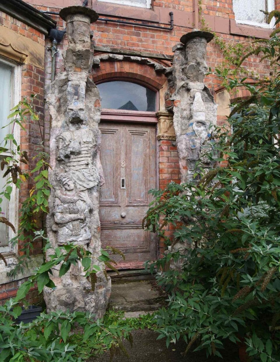 hand-sculpted concrete figurative columns flanking the wooden door of Ron Gittins' apartment in England