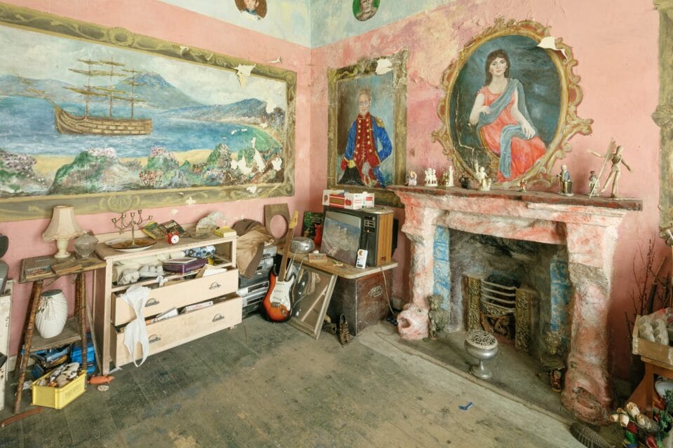 the interior of Ron Gittins' apartment in Birkenhead, England, the walls of which are painted with a colorful, romantic mural of painted portraits above an ornate fireplace