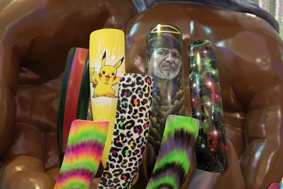 a detail of a large sculpture of a Black person's hands showing large fingernail designs with imagery ranging from Pikachu to leopard print