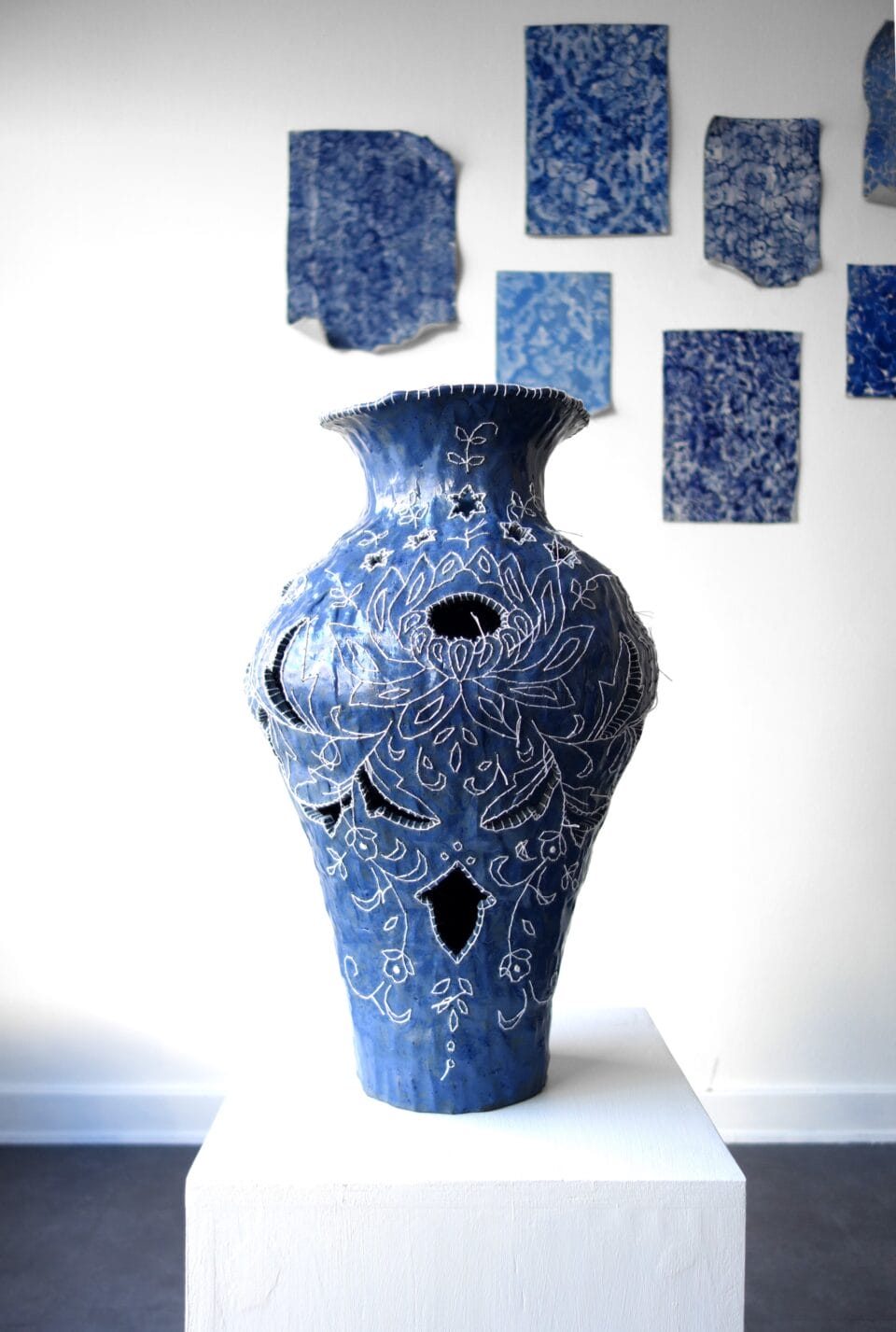 a blue porcelain vessel embroidered with white cotton thread