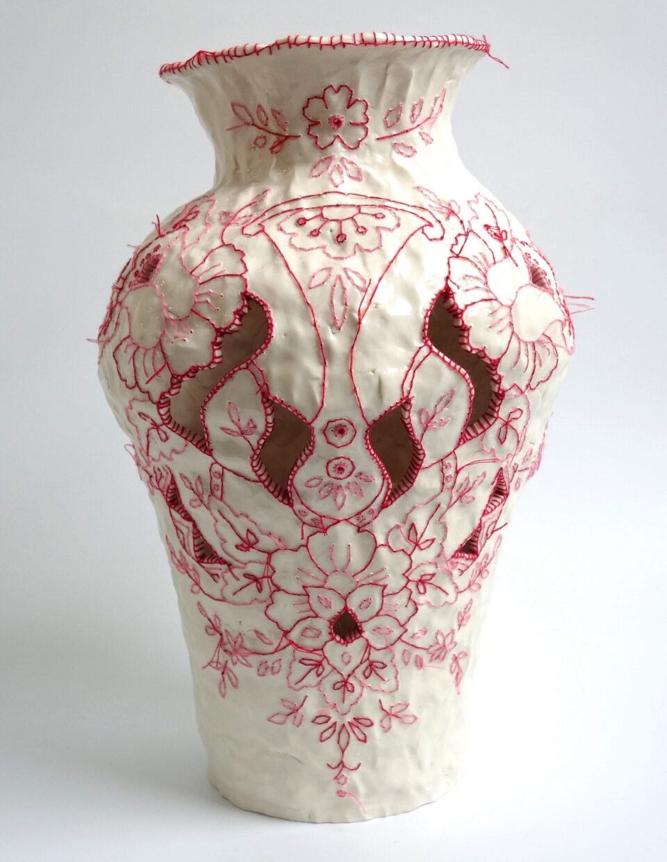 a white porcelain vessel embroidered with red cotton thread