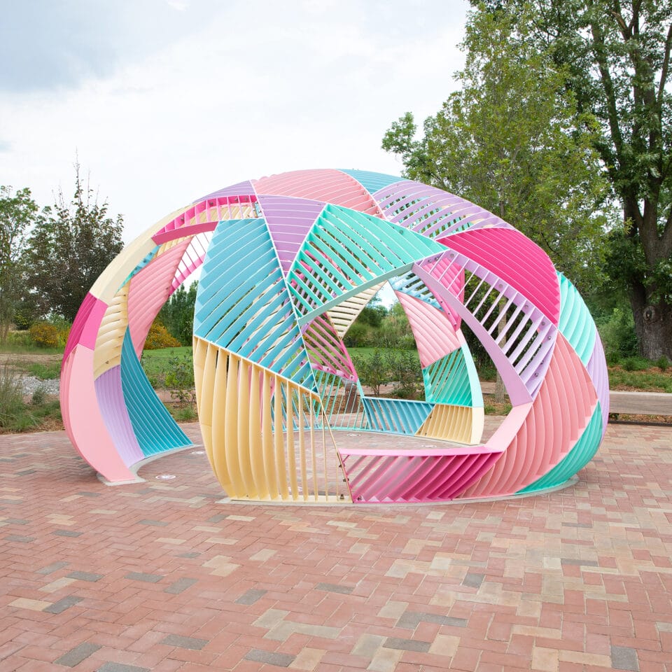 a colorful geometric outdoor dome structure made of metal with different geometric facets and openings