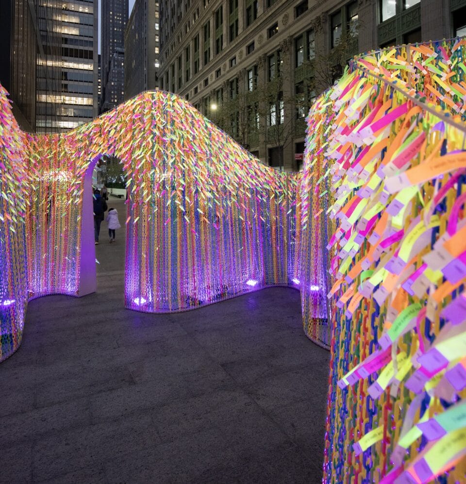 an outdoor installation of undulating, permeable walls with some doorways that are lit up at night