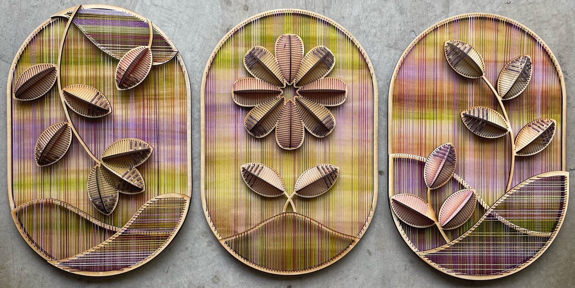 a trio of vibrant embroidered sculptural flowers on wood oval panels