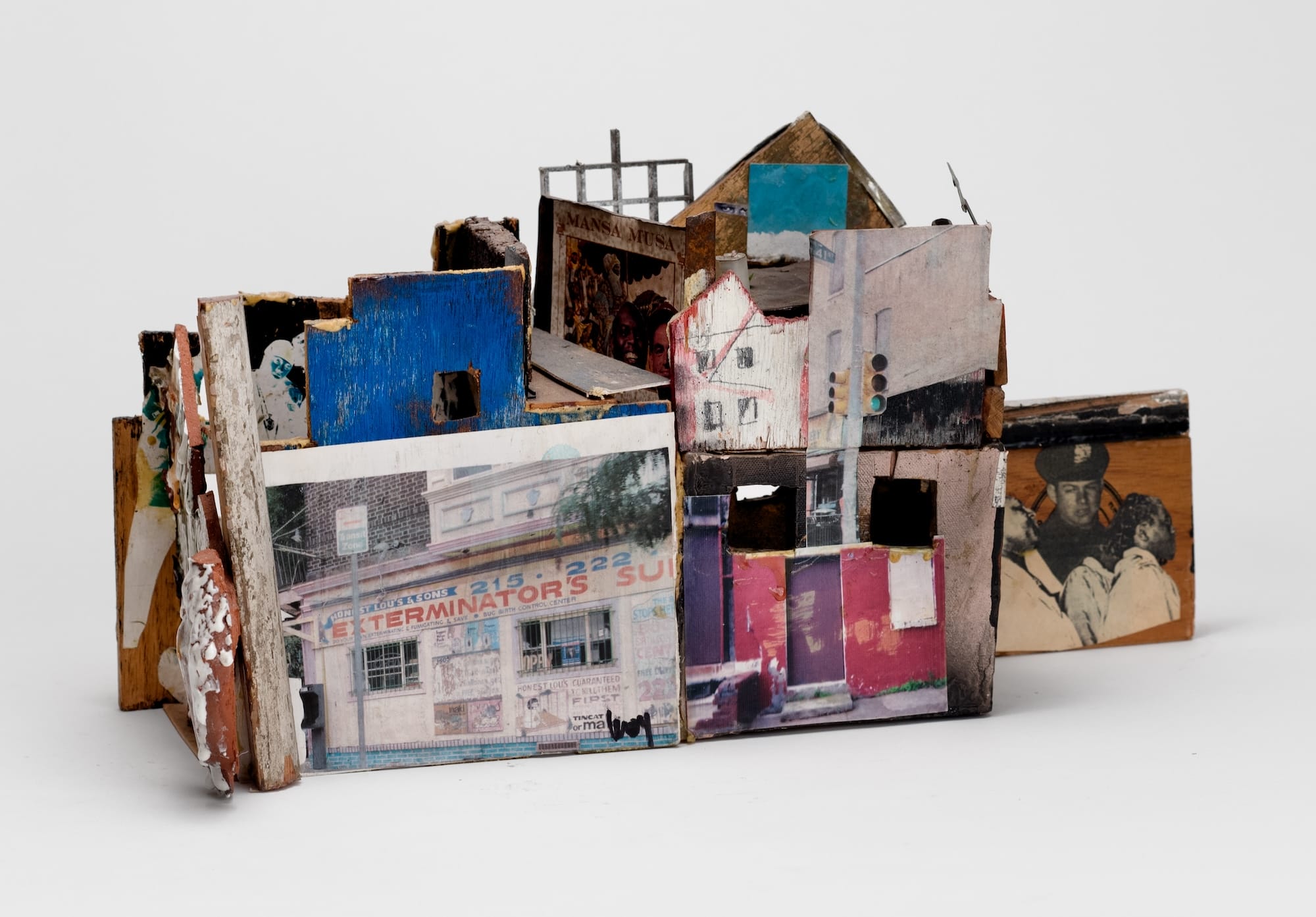 a sculpture of an abstract house made from ceramics, found objects, photographs, and other mixed media