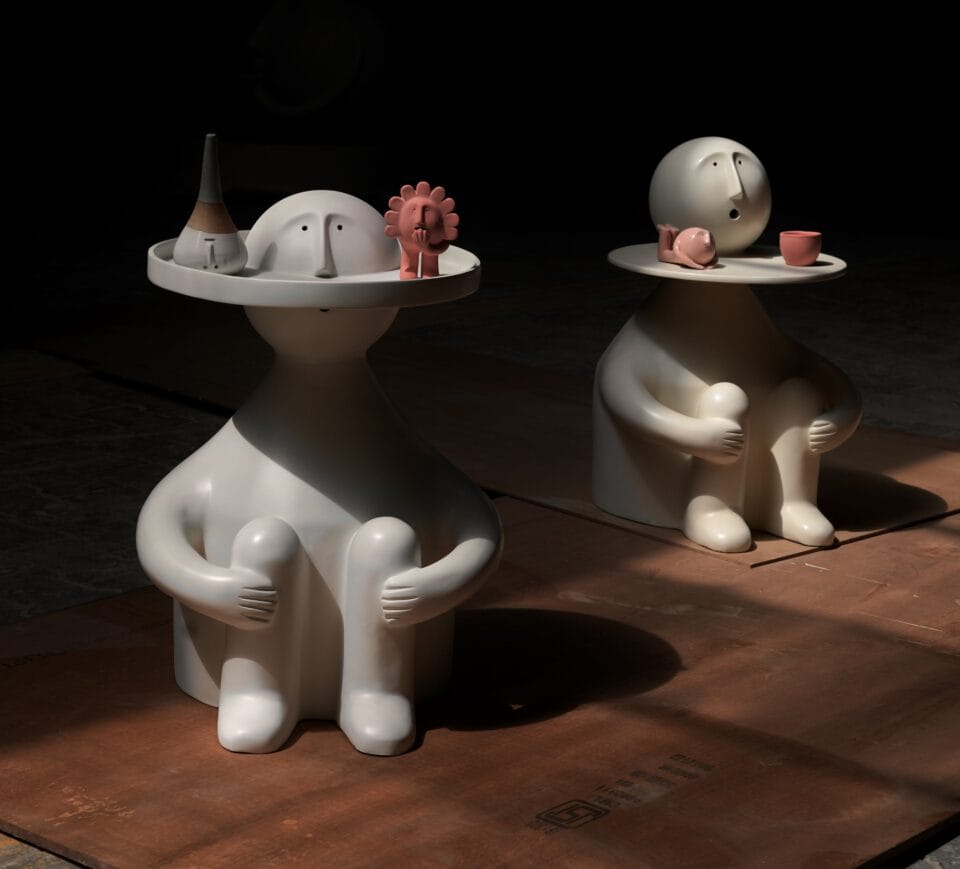 two ceramic figures sit with a functional tray encircling their heads.