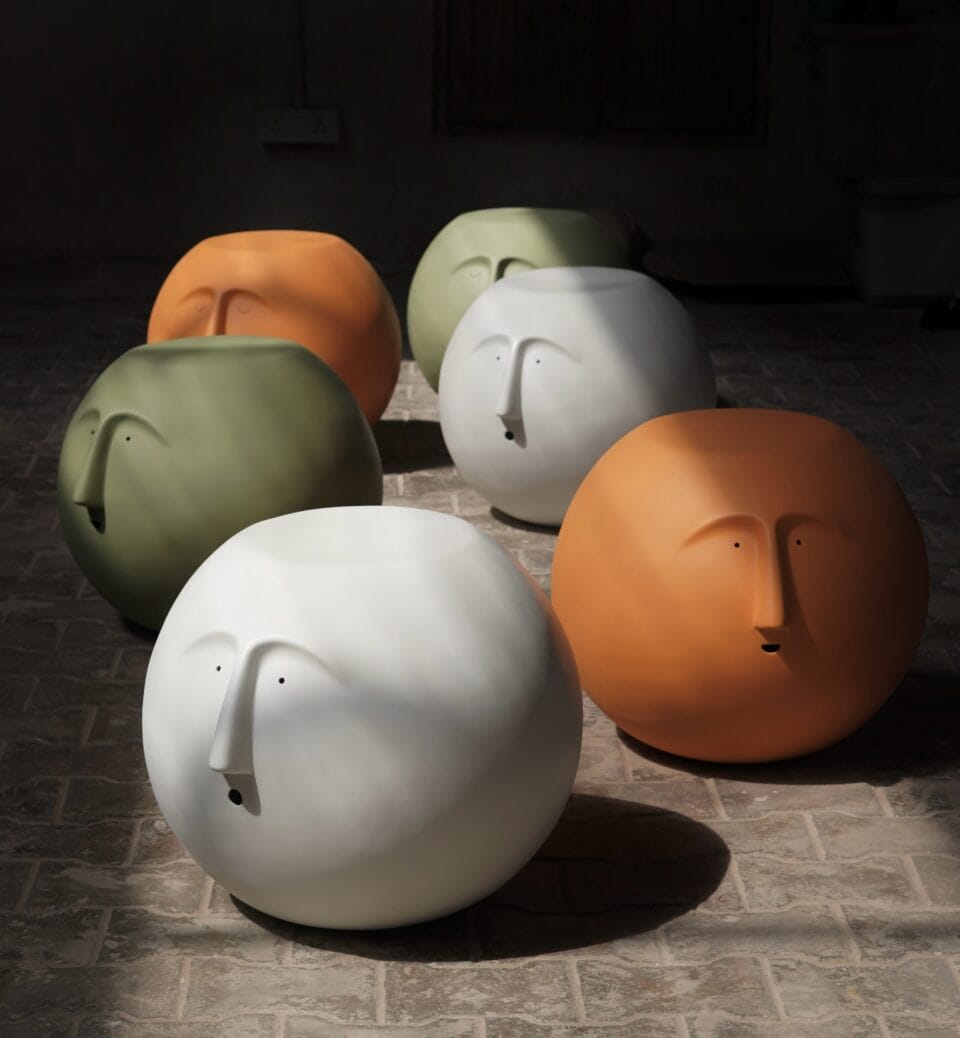 six heads in hues of ivory, sage green, and orange take the form of spherical seats