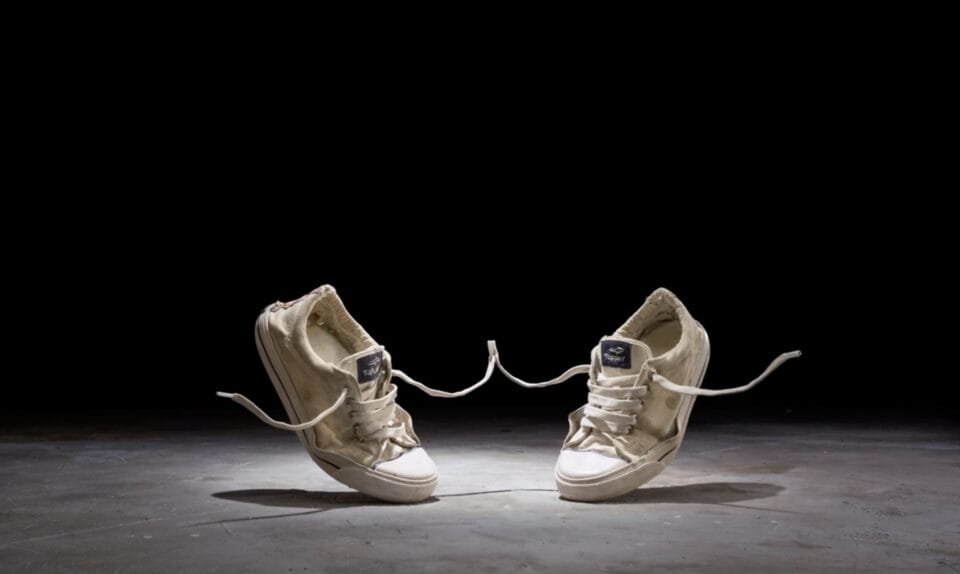 a still from a stop-motion animated short of two canvas sneakers dancing against a black background