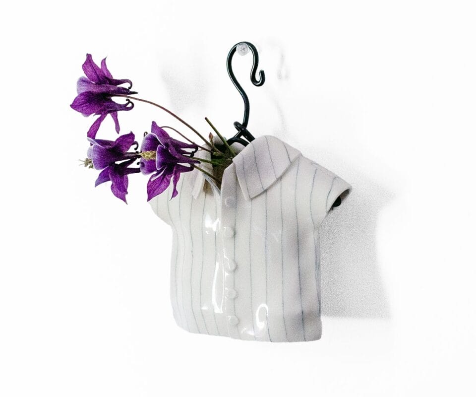 a tiny button up shirt on a hanger holds flowers