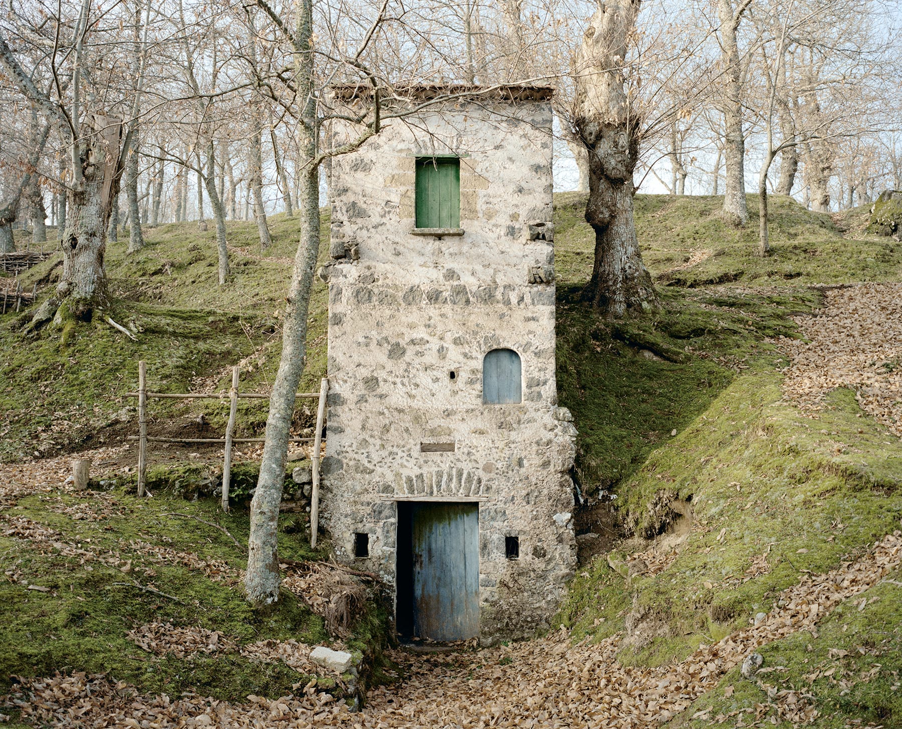 a photograph of a solitary, three-story, stone house in the Italian countryside