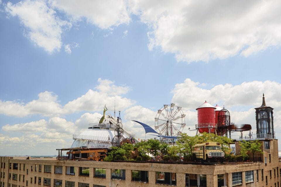 a bus, ferris wheel, red silo and more perch atop a building