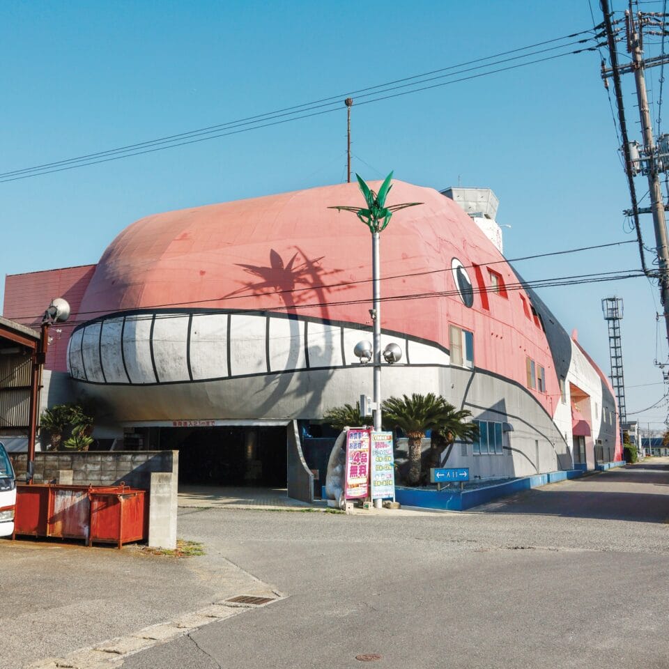 the facade of a love hotel in Japan along the roadside shaped like a giant pink whale