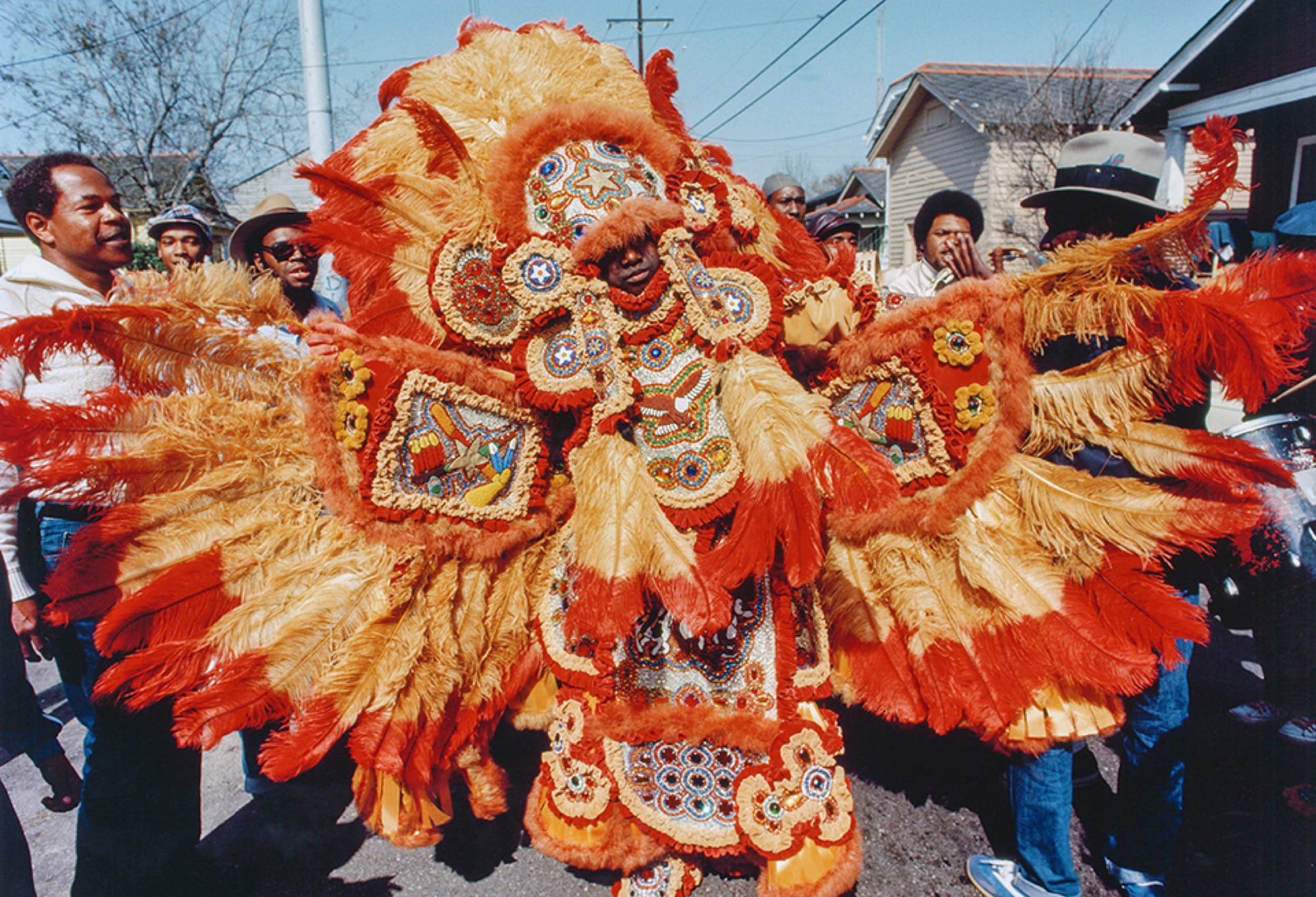 Larry Bannock, Big Chief of the Golden Star Hunters at Mardi Gras in New Orleans, dances in an elaborate costume made of orange and yellow feathers and patterns of beads