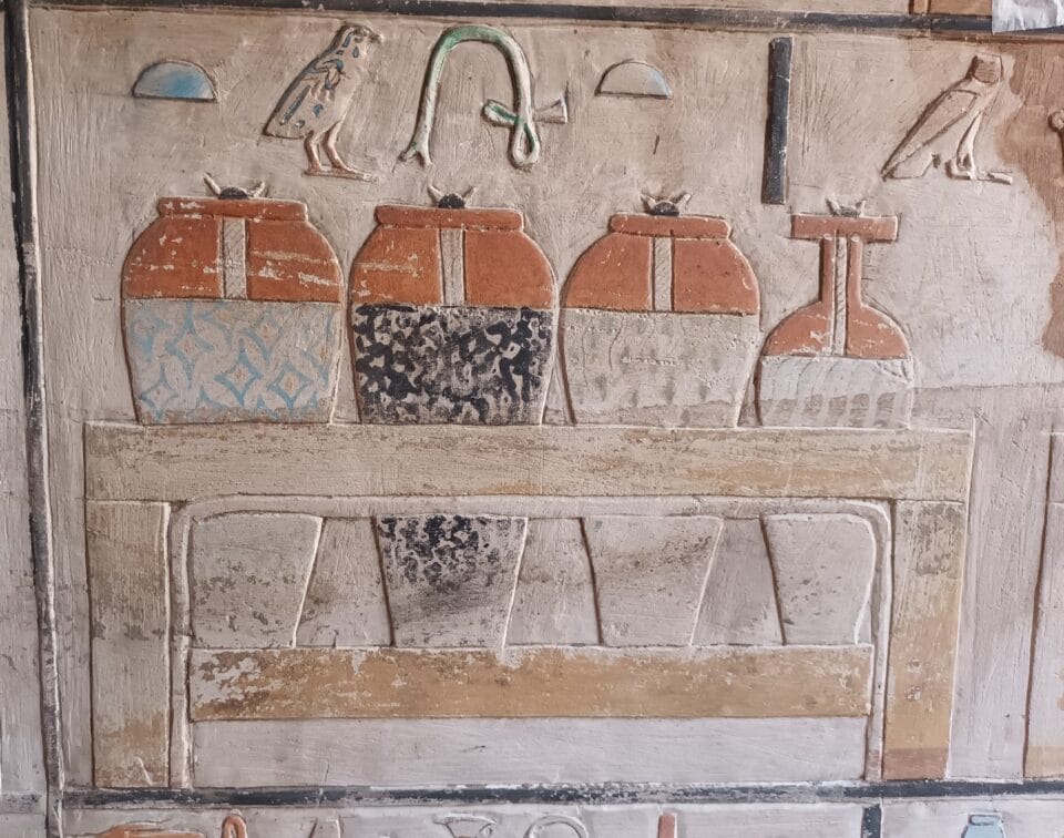 painted stone relief carvings of urns, hierogylphs, and furniture in an ancient Egyptian tomb