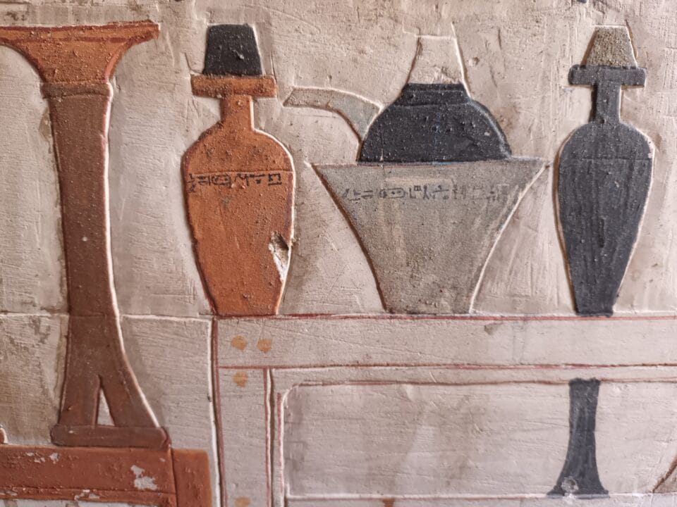 painted stone relief carvings of urns and furniture in an ancient Egyptian tomb