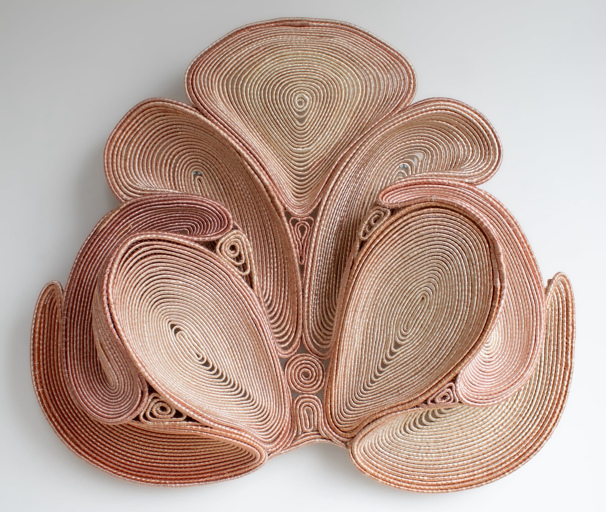 a symmetric pink coiled wall sculpture