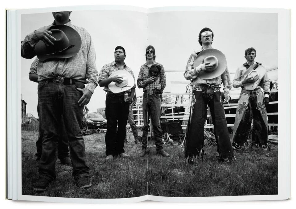 an open book spread with a black and white photo of cowboys holding their hats over their hearts