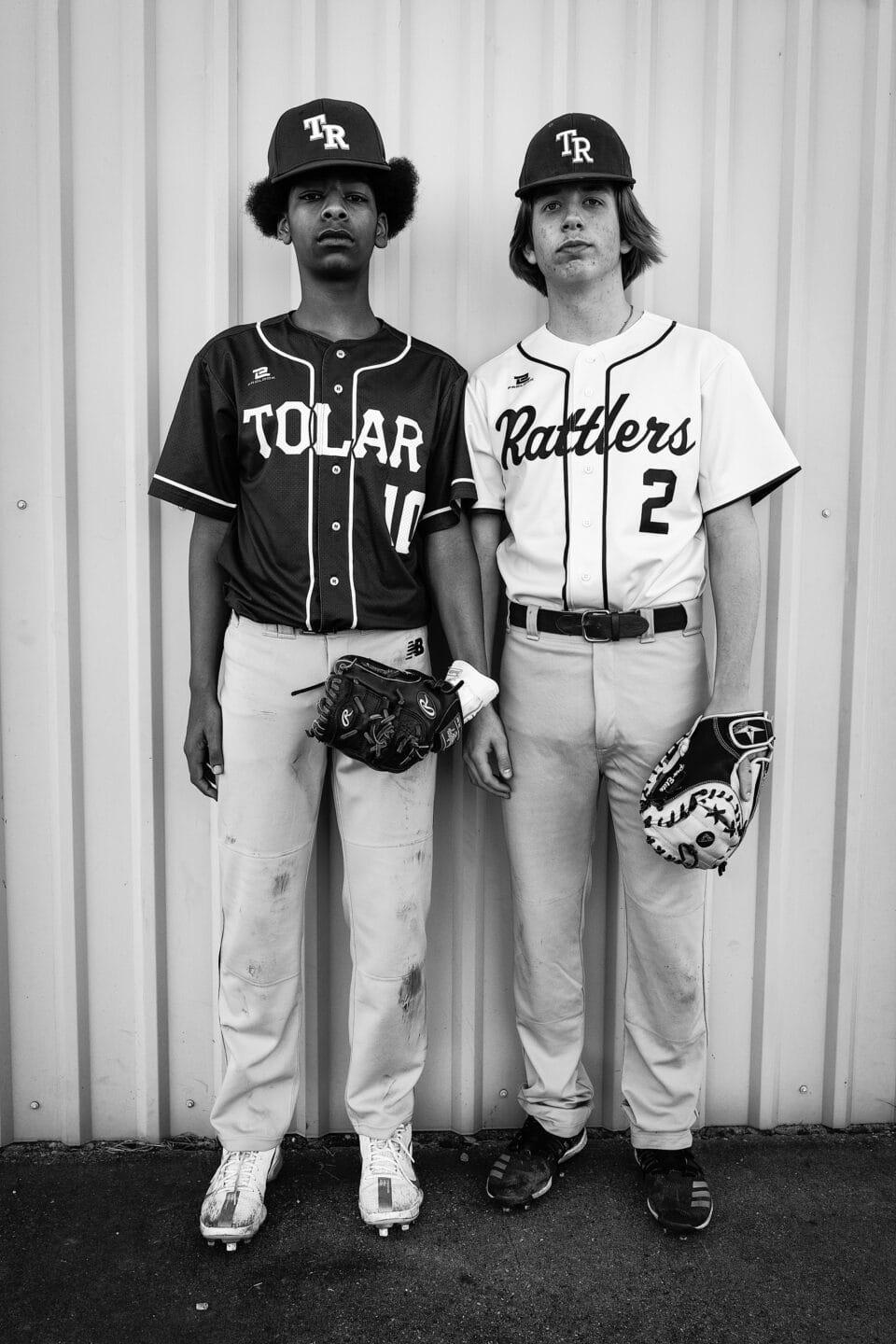 a black and white photo of two young male baseball players