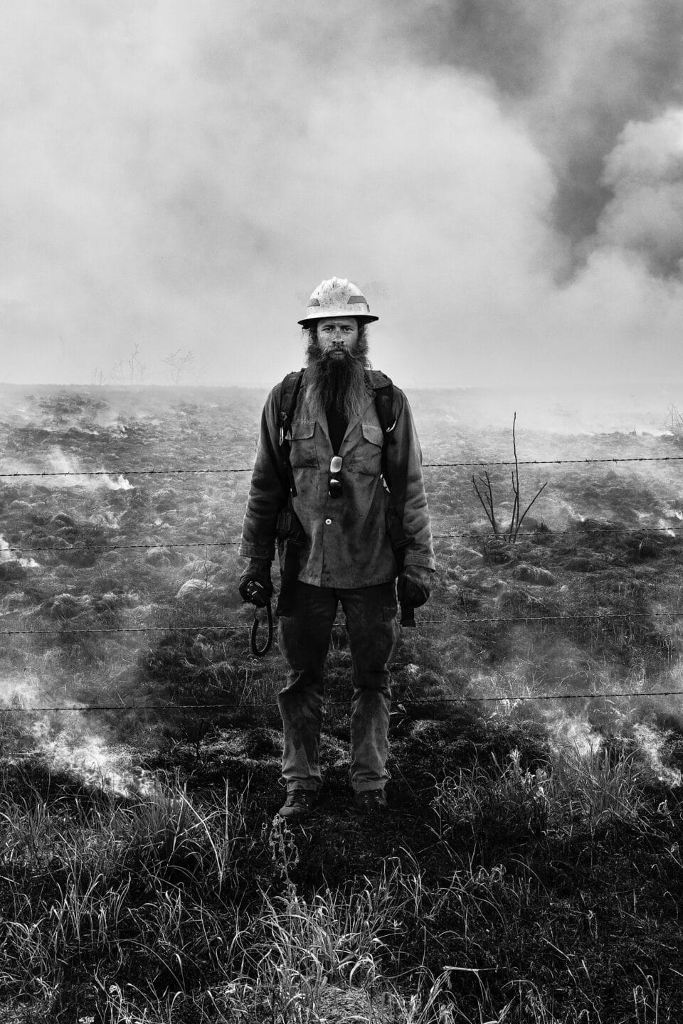 a black and white photo of a firefighter in a burning field