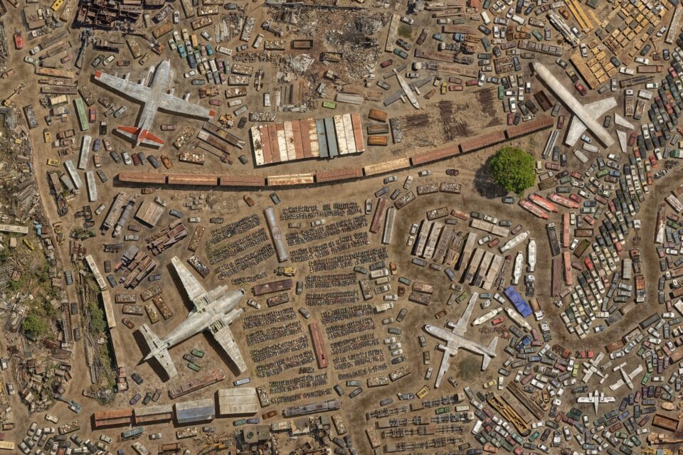 a detail of a large-scale, digitally created aerial composite image of numerous junkyards, scrap metal yards, and disused airplanes and vehicles