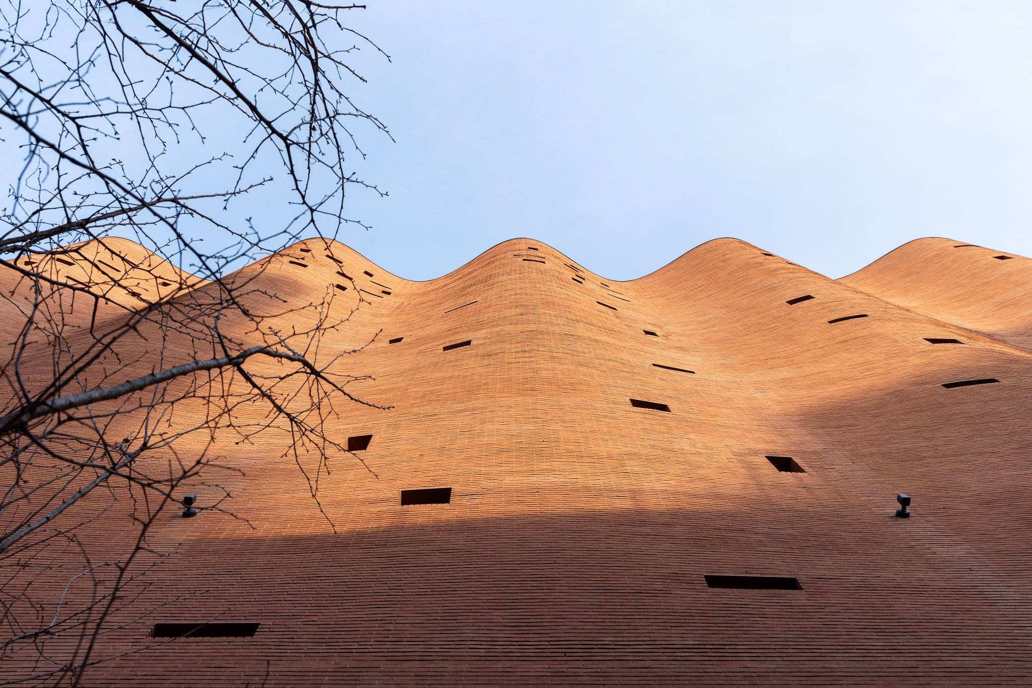 looking up at a curtain-like brick facade with tiny scattered windows on a building in Seoul