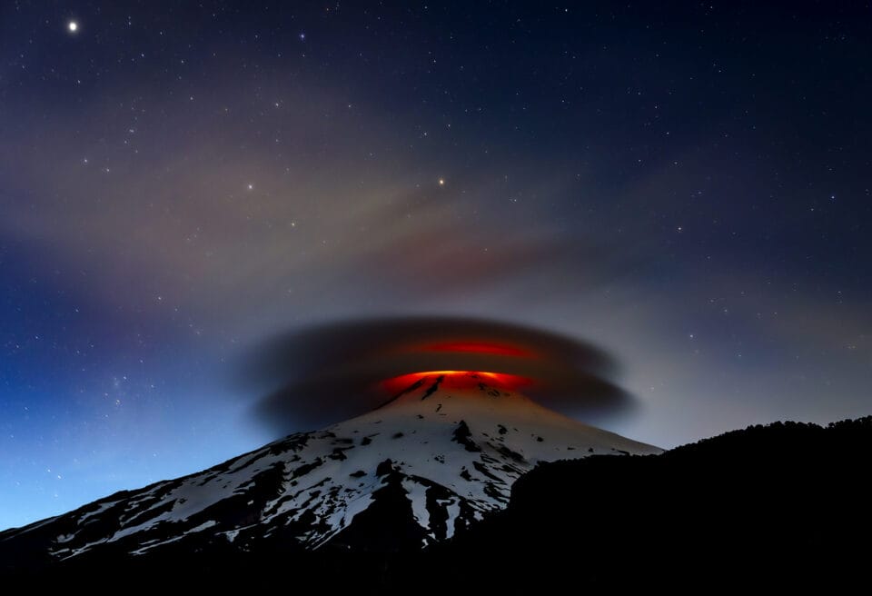 
A double lenticular cloud is illuminated at nightfall by the lava emitted from the Villarrica volcano, Chile. 