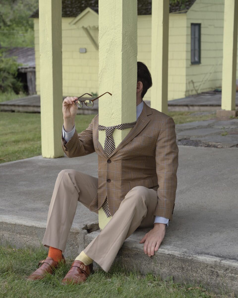 a man in a suit has his jacket buttoned around a yellow post